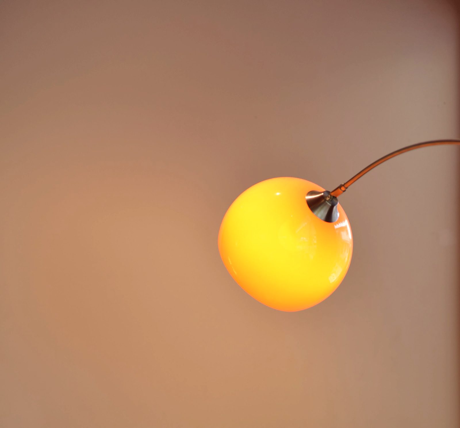 A cozy cafe interior featuring a modern lamp illuminating a small table with a drink.