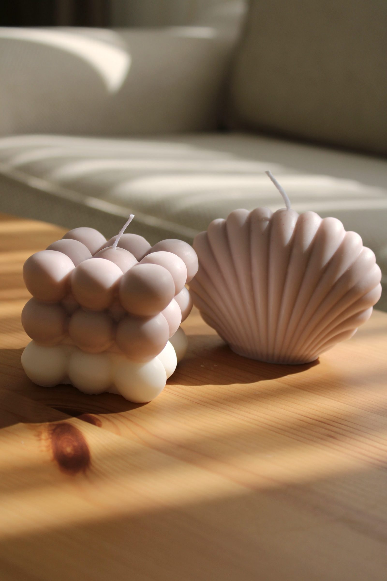 Sculpted candles on a wooden coffee table in a sunlit living room.