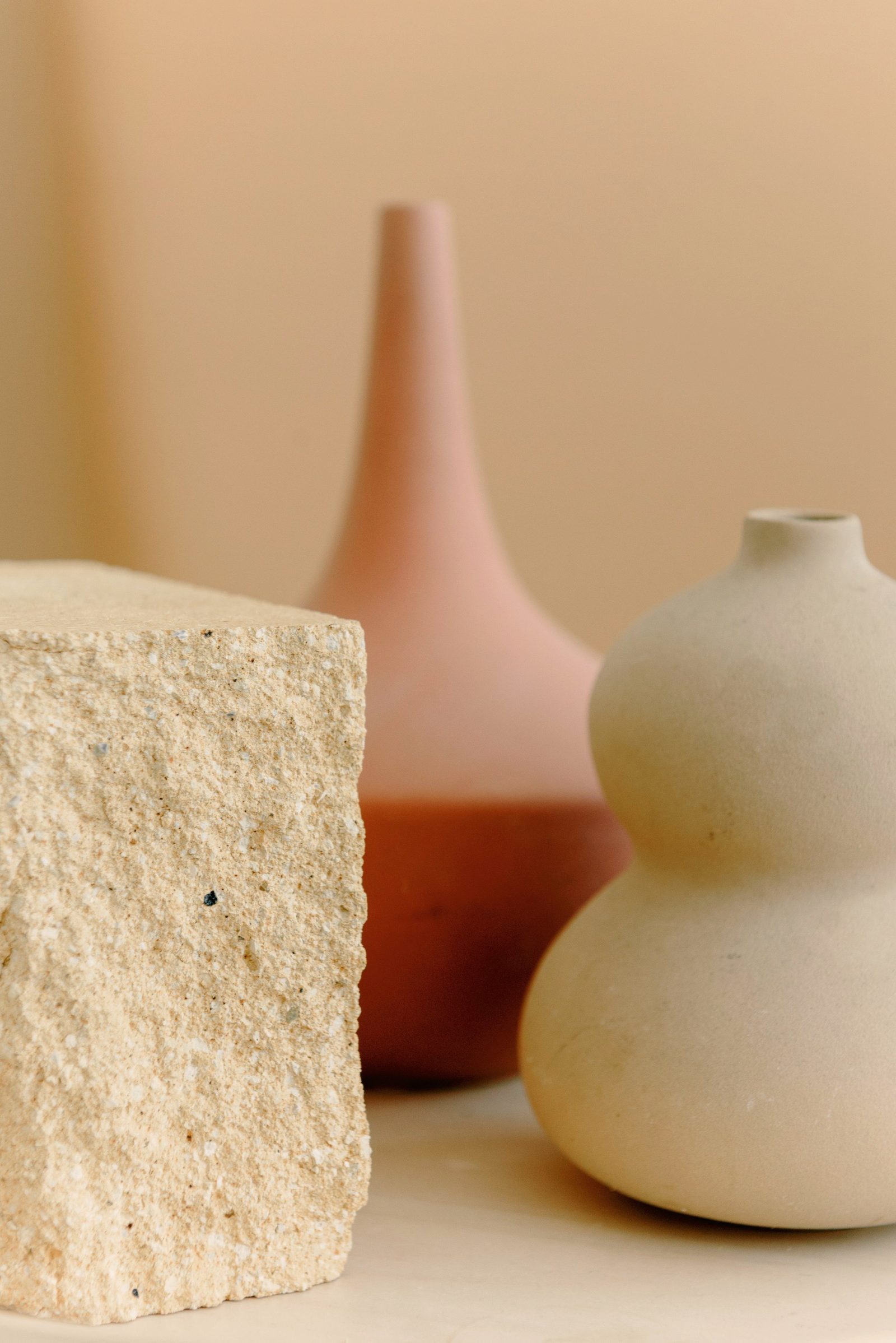 A textured stone cube beside two sculptural ceramic vases